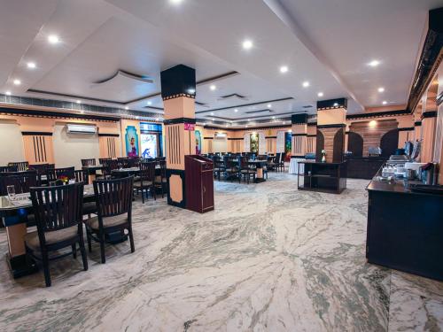 a restaurant with tables and chairs in a large room at NRS Royal Palace in Puri