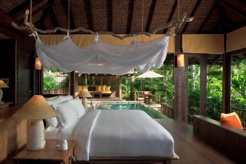 a bedroom with a bed and a swimming pool at Six Senses Yao Noi in Ko Yao Noi