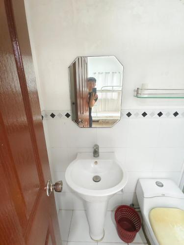 a man taking a picture of a bathroom with a sink at Best Inn Lahug in Cebu City
