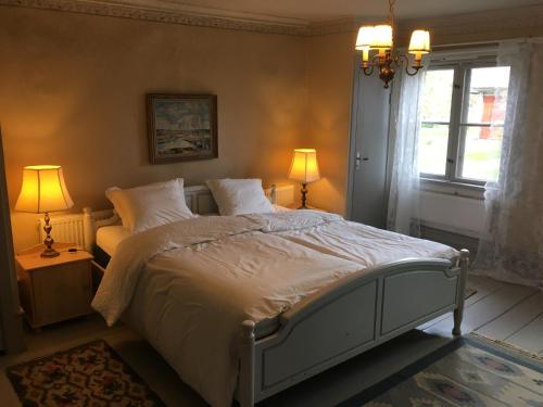 ein Schlafzimmer mit einem Bett, zwei Lampen und einem Fenster in der Unterkunft Professorsvillan - hyr hela huset in Malingsbo