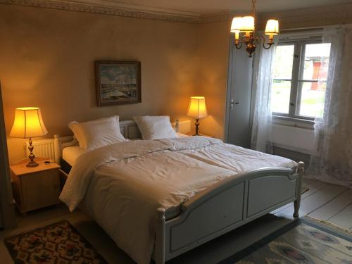 a bedroom with a bed and two lamps and a window at Professorsvillan - hyr hela huset in Malingsbo