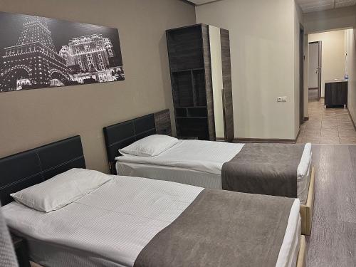 a bedroom with two beds and a painting on the wall at Bien hotel in Yerevan