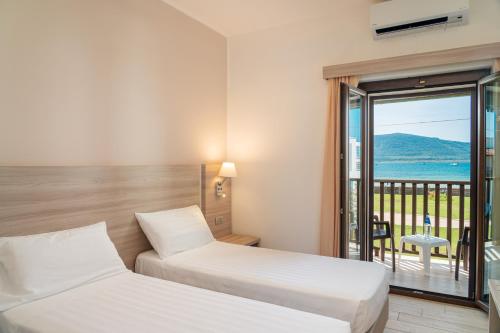 a hotel room with two beds and a balcony at Hotel Portoconte in Porto Conte