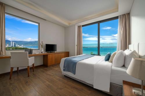 a hotel room with a bed and a desk and a large window at Stunning Apartments Across My Khe Beach ! Rooftop Pool & Gym in Da Nang