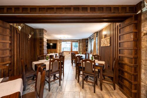 um restaurante com paredes e mesas e cadeiras de madeira em Beluga Guest House em Velingrad