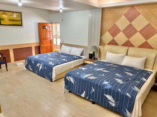 a hotel room with two beds with blue and white sheets at TREE HOUSE in Pingtung County