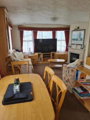 a living room with a table and a television at Warden spring in Leysdown-on-Sea