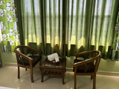 duas cadeiras e uma mesa em frente a uma cortina em Zu-Zu Hostels em Shimla