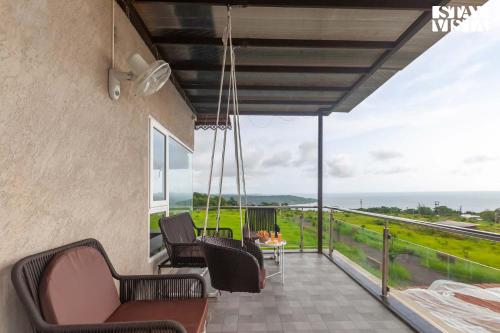 Un balcón con sillas y una mesa con vista. en StayVista's Coral Breeze with Plunge Pool, Games Room, Projector Setup, Proximity to Secluded Beach, en Dapoli
