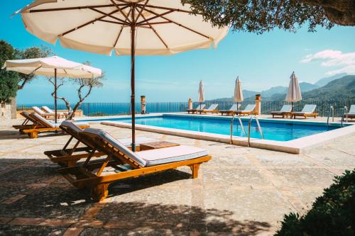 einen Pool mit Stühlen, einem Sonnenschirm und einem Pool in der Unterkunft Sa Pedrissa in Deià