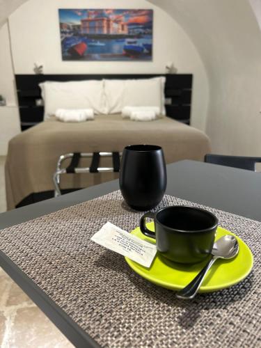 a black cup on a yellow plate on a table with a bed at Cantovì in Bari