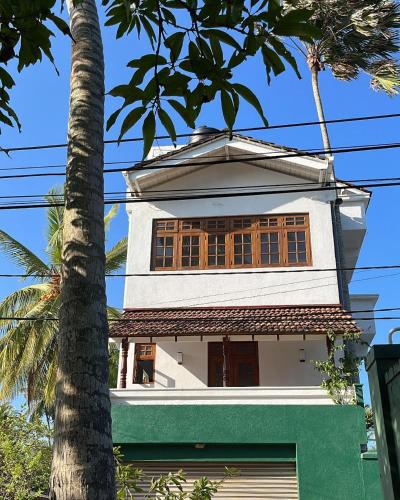a white house with a tree in front of it at Beach Club Apartments in Induruwa