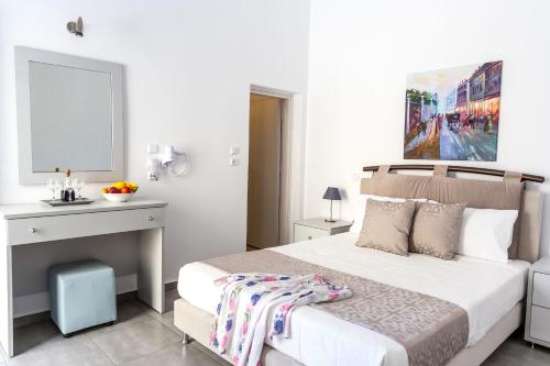 a white bedroom with a bed and a desk at Aigli Villa in Fira