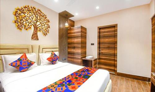 a bedroom with a large bed with a tree on the wall at FabHotel Jalsa Residency New Town in Kolkata