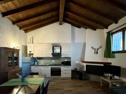 une cuisine avec des placards blancs et une table. dans l'établissement La Corte della Casera, à Cassina Valsassina
