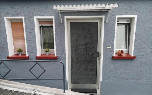 ein graues Gebäude mit zwei Fenstern und einer Tür mit einer Katze drauf in der Unterkunft Apartment Am Radweg in Wetzlar