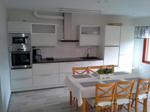 a kitchen with white cabinets and a table and chairs at Karemajat Panorama hotel in Ylitornio