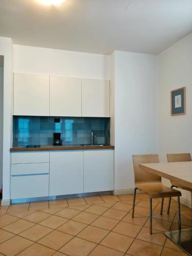 a kitchen with white cabinets and a table at Aquazzurra Resort & Aparthotel in Cannobio