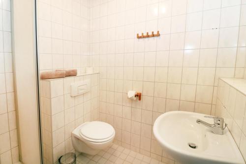 a white bathroom with a toilet and a sink at Ferienwohnung Naturparadies Gnitz in Lütow
