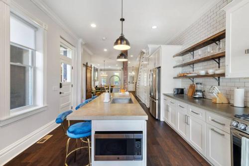 a kitchen with white cabinets and a island with blue chairs at 6min to Pittsburgh Zoo l A block from Butler St in Pittsburgh