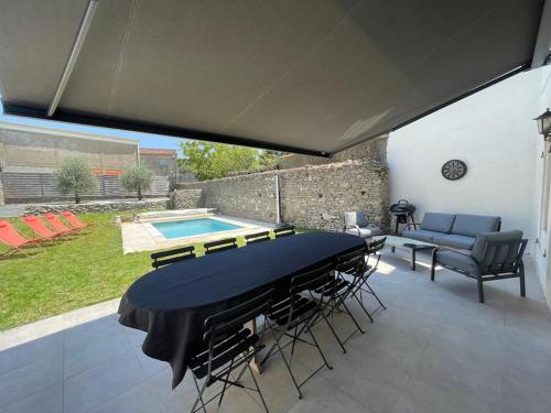 um pátio com uma mesa e cadeiras e uma piscina em Piscine privée sans vis à vis / Calme / Babyfoot em Conques-sur-Orbiel