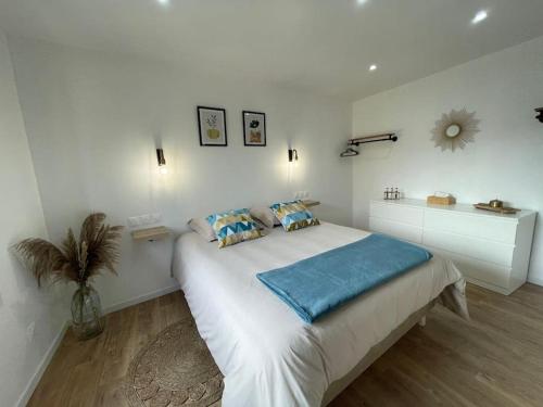 une chambre blanche avec un grand lit avec des oreillers bleus dans l'établissement La Casa di Maria - Gîte 2 à 4 personnes, à Lespesses