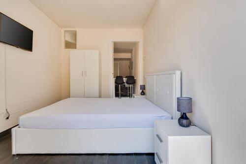 a white bedroom with a bed and a night stand at Appartamento 5 stelle Barcola - 50 meters from the sea in Trieste