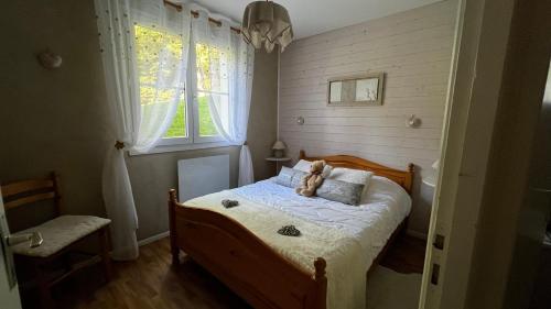 um quarto com uma cama com um urso de peluche em Les Prairies du lac em Gérardmer