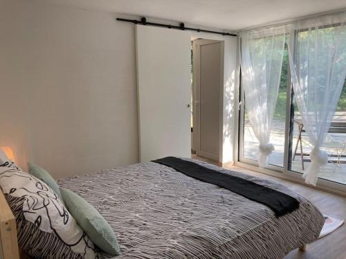 Ventenac-CabardèsにあるPlein cœur de la nature ~ Jacuzzi Privé 24h/24hのベッドと大きな窓のある寝室