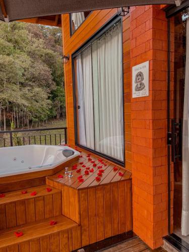 a bathroom with a tub and a window with red candles at Pousada e Restaurante Casa Cida e Evandro in Gaspar