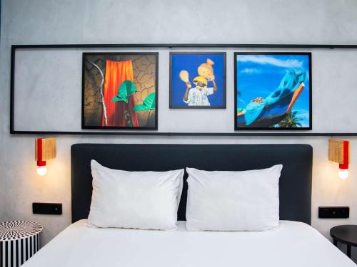 1 dormitorio con 1 cama con 4 cuadros en la pared en Ibis Styles Abidjan Plateau, en Abiyán