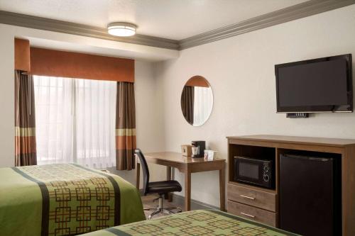 a hotel room with a bed and a desk and a tv at Super 8 by Wyndham Santa Clarita/Valencia in Santa Clarita
