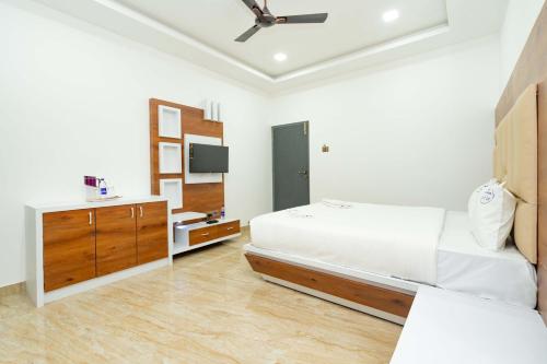 a white bedroom with a bed and a dresser at HOTEL NATCHATHRA in Rāmeswaram