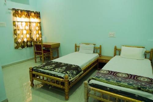 - deux lits assis l'un à côté de l'autre dans une pièce dans l'établissement ISKCON Pandharpur's Chandrabhaga Guest House, à Pandharpur