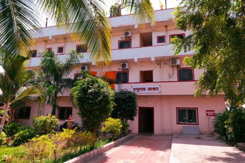 a pink building with trees in front of it at ISKCON Pandharpur's Chandrabhaga Guest House in Pandharpur