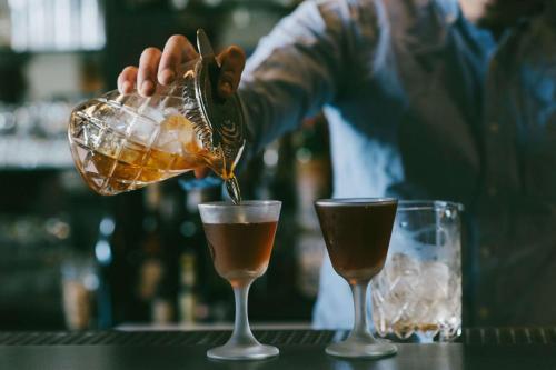 a bartender is pouring a drink into two glasses at Canopy By Hilton Chicago Central Loop in Chicago