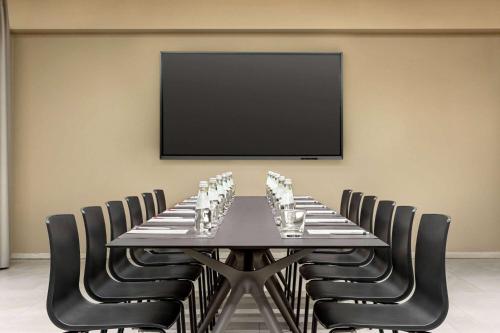 a conference room with a table with chairs and a flat screen tv at Amedia Hotel Milan, Trademark Collection by Wyndham in Milan