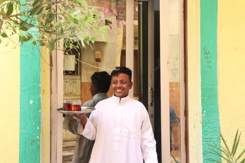 un homme tenant une assiette de nourriture dans une porte dans l'établissement SWEET HOSTEL LUXOR, à Louxor