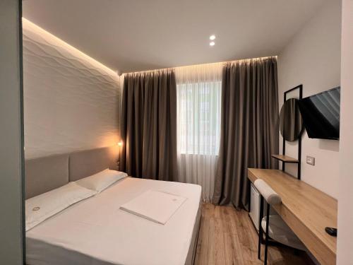 1 dormitorio con cama blanca y ventana en D Rooms en Tirana
