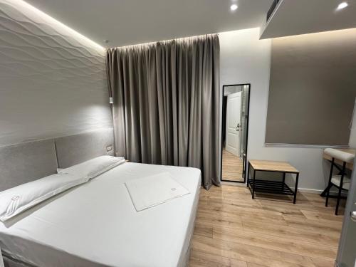 a bedroom with a large white bed and a table at Enzo rooms & apartment Blloku in Tirana