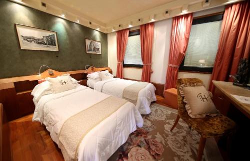 a hotel room with two beds and a chair at HR Hotel in Monfalcone