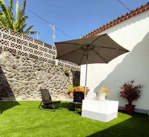 a patio with an umbrella and chairs on grass at La casa de Isabel in Mazo