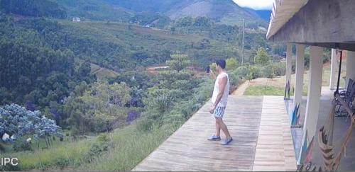 Un uomo in piedi su un portico che guarda una valle di Refúgio do ipê (Barboza & Castro) a Espera Feliz