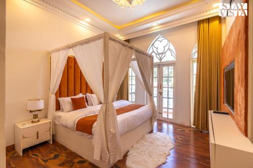 una camera con letto a baldacchino di StayVista's Udaan Manor with Outdoor Pool, Jacuzzi & Lush Lawn with Gazebo & Bar a Chandīgarh