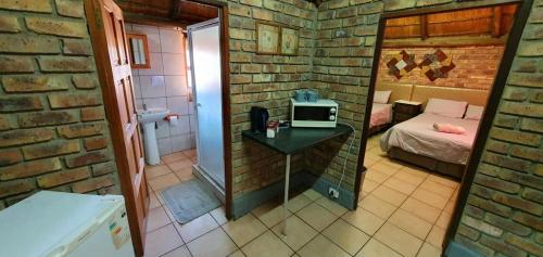 a small room with a bed and a table with a microwave at Pepe Piatto Lodge in Grootvlei