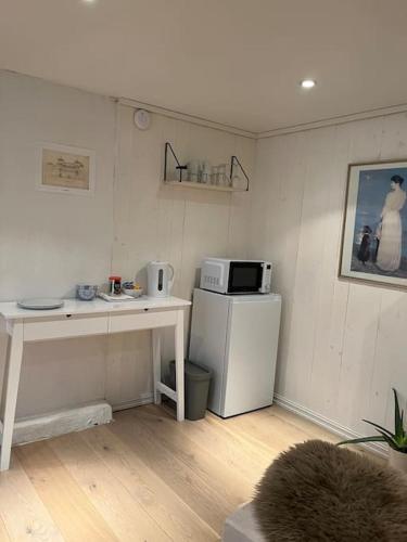 a kitchen with a refrigerator and a table with a microwave at Hybel med bad in Egersund