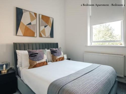 a bedroom with a large white bed with two windows at Lux Bermondsey Apartments Near Tower Bridge in London