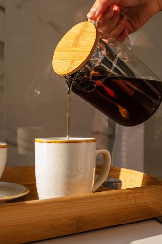 a person pouring coffee into a cup on a wooden tray at Infinity View Apartment in Naxos Chora