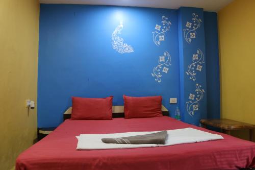 a bed with red pillows and a blue wall at Hotel Hill Side in Hazārībāg