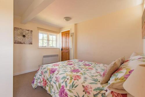 a bedroom with a bed with a floral bedspread at The Bothy - Charming home on a working farm in Faversham